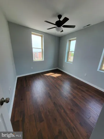 a view of empty room with wooden floor and fan