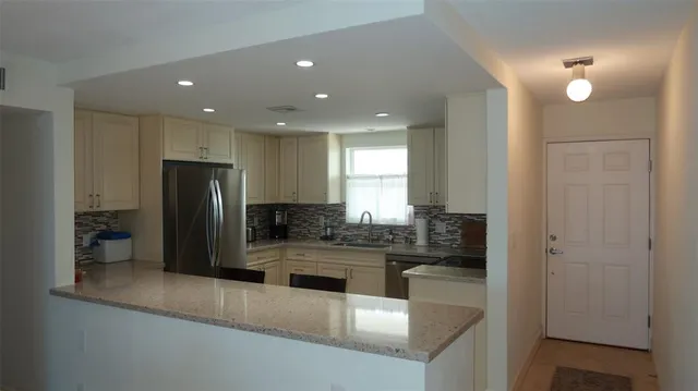 a kitchen with stainless steel appliances granite countertop a refrigerator and a sink