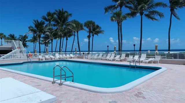 a view of a swimming pool with a chair and potted plants