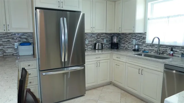 a kitchen with stainless steel appliances granite countertop a refrigerator and a sink