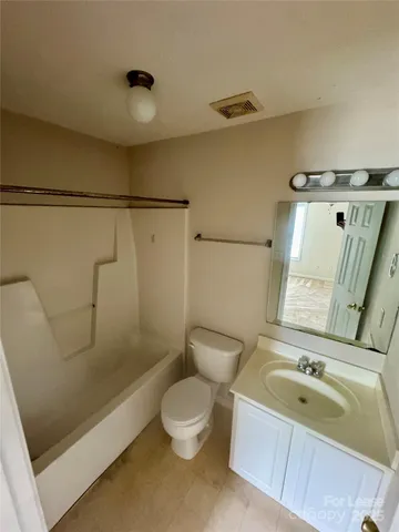 a bathroom with a granite countertop bathtub shower sink vanity and toilet