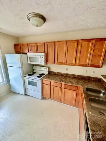 a kitchen with granite countertop a stove a sink and a microwave