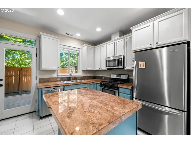 a kitchen with granite countertop a refrigerator and a stove top oven