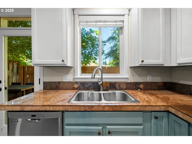 a kitchen with granite countertop a sink and a white cabinets
