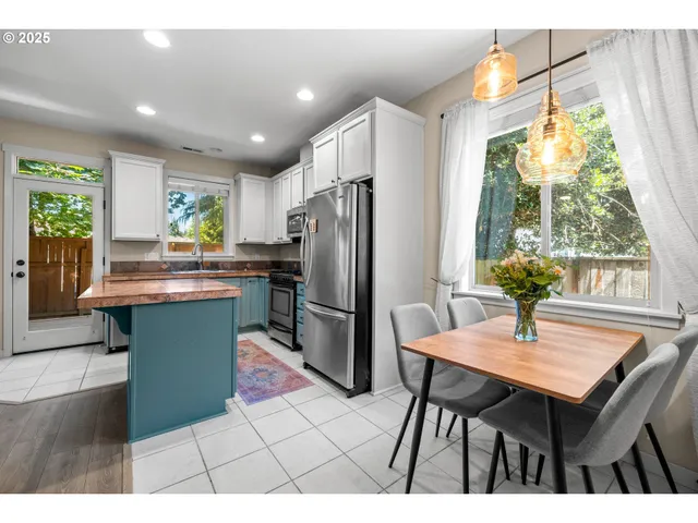 a kitchen with stainless steel appliances kitchen island granite countertop a table chairs and a refrigerator