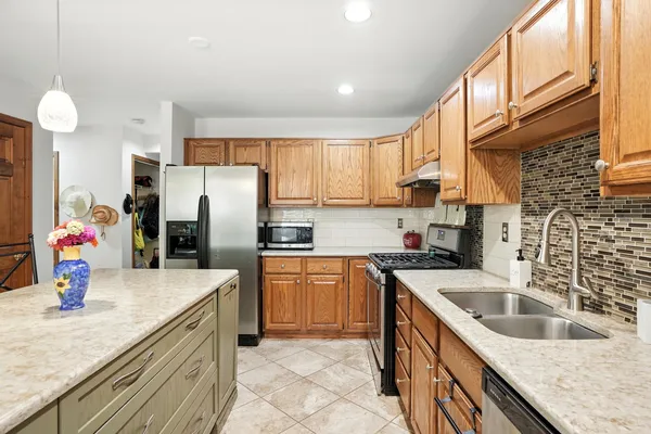 a kitchen with stainless steel appliances granite countertop a sink refrigerator and cabinets