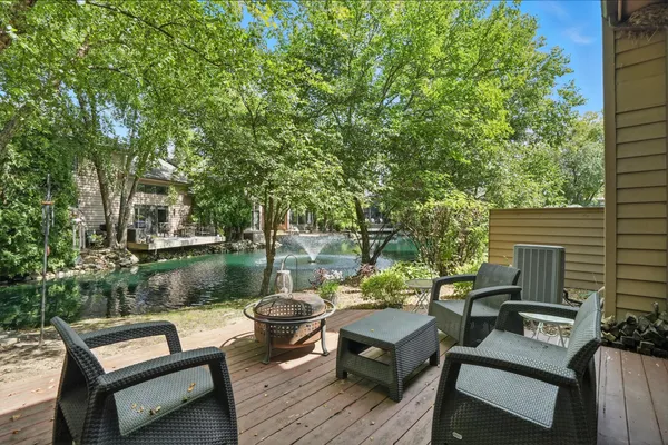 a view of a patio with couches chairs and a table and chairs with wooden floor and fence
