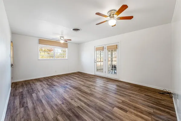 a view of an empty room with window and wooden floor