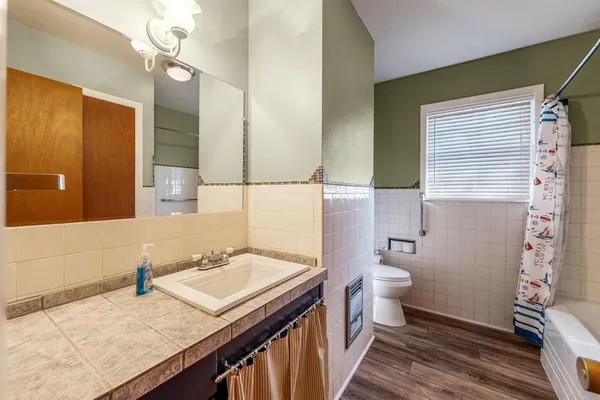 a bathroom with a granite countertop sink a toilet a mirror and shower