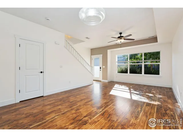 a view of an empty room with a window and wooden floor