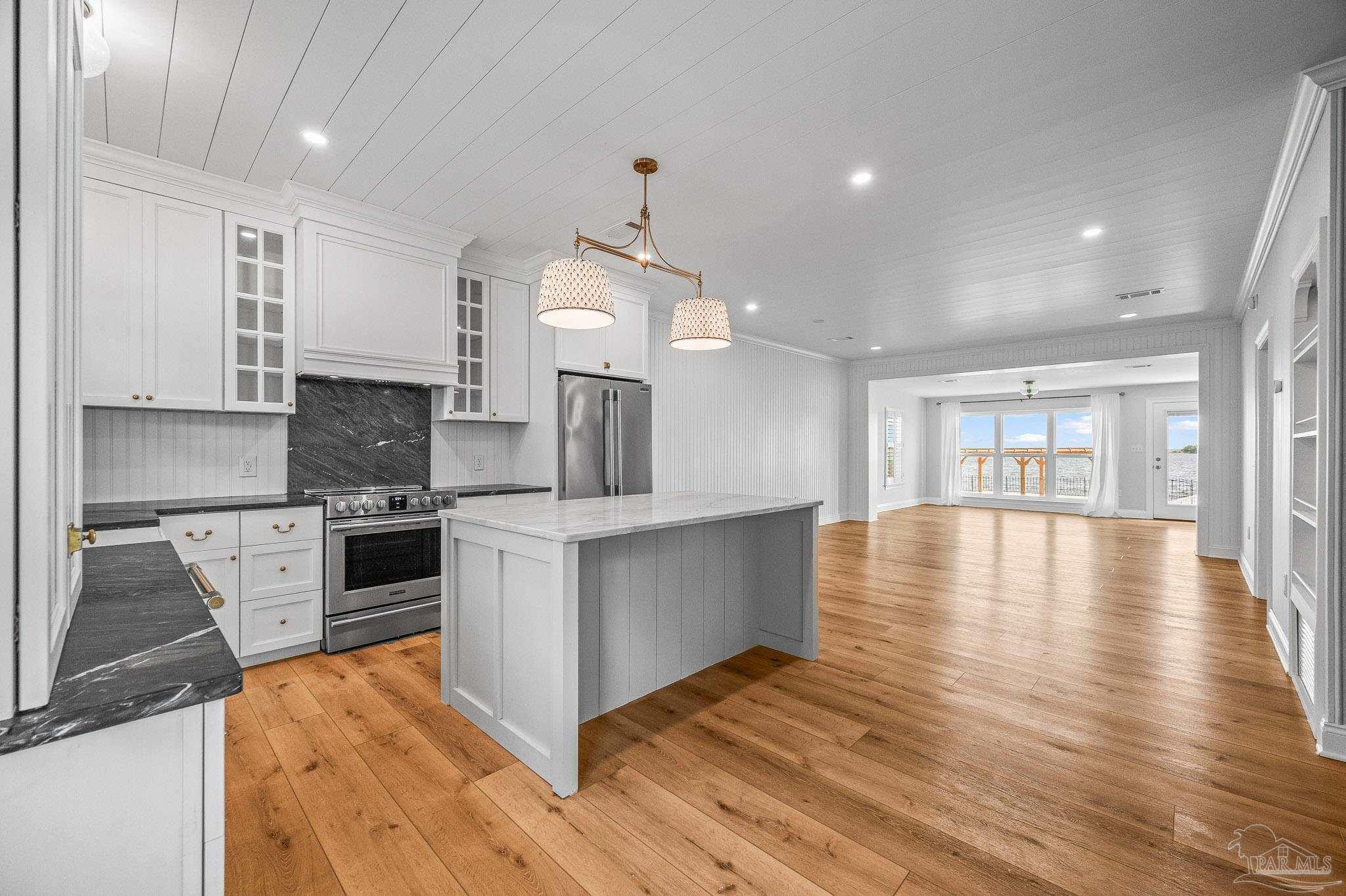 7693 Petersen Point Road Milton, FL 32583 - Photo 11 of 58 a kitchen with stainless steel appliances granite countertop a stove top oven a sink dishwasher a refrigerator and a dining table with wooden floor