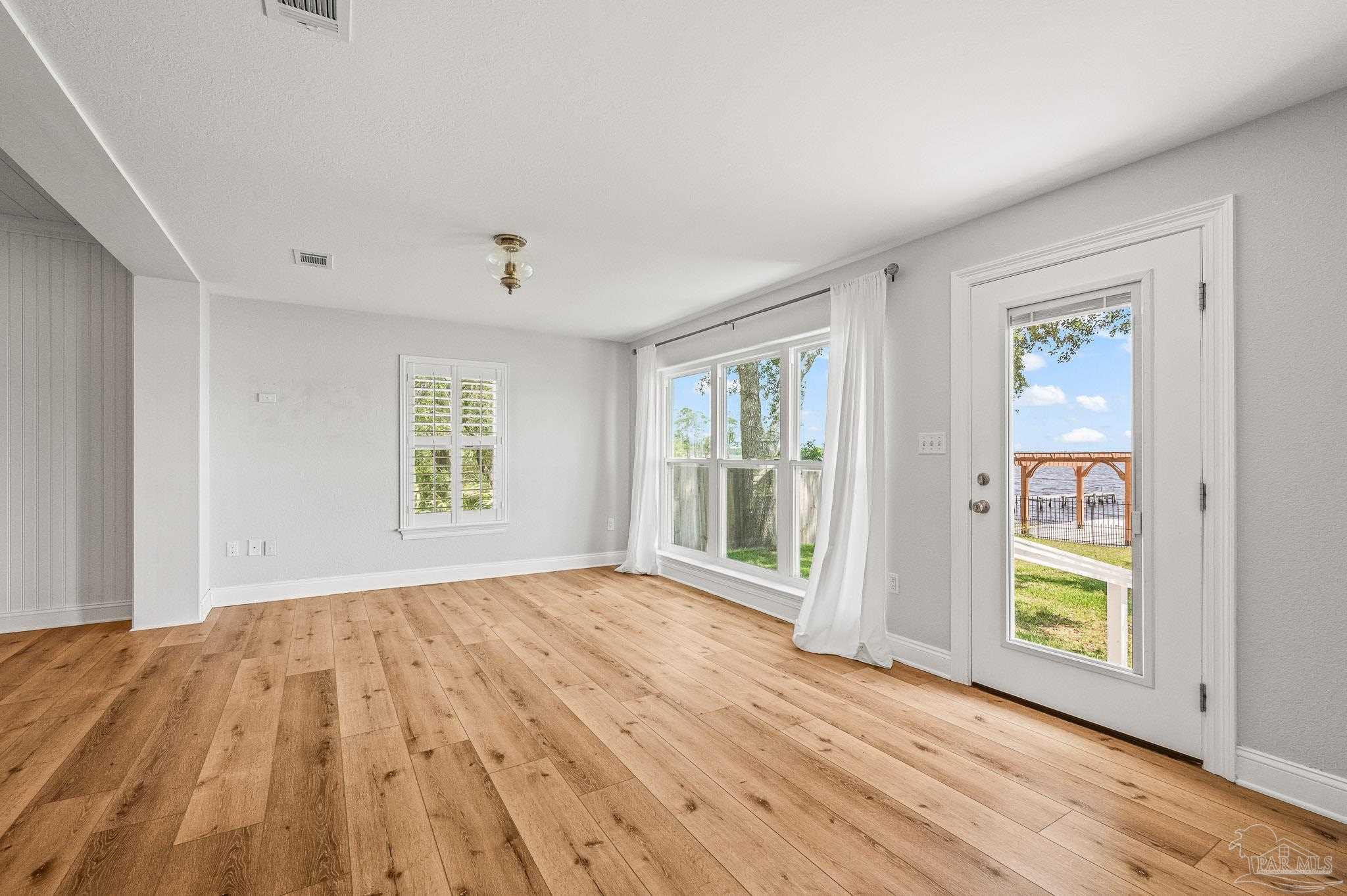 7693 Petersen Point Road Milton, FL 32583 - Photo 15 of 58 a view of an empty room with a window and wooden floor