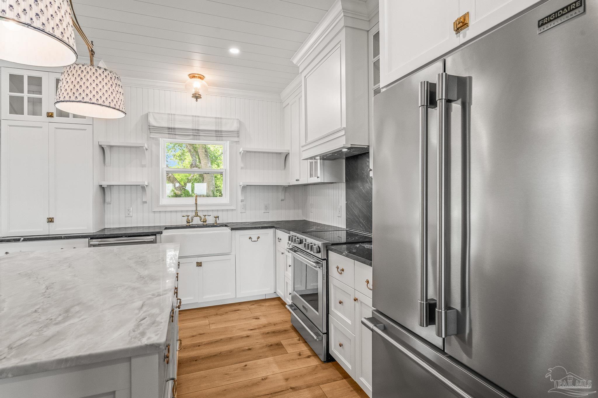 7693 Petersen Point Road Milton, FL 32583 - Photo 8 of 58 a kitchen with stainless steel appliances granite countertop a refrigerator a sink dishwasher a stove and white countertops with wooden floor