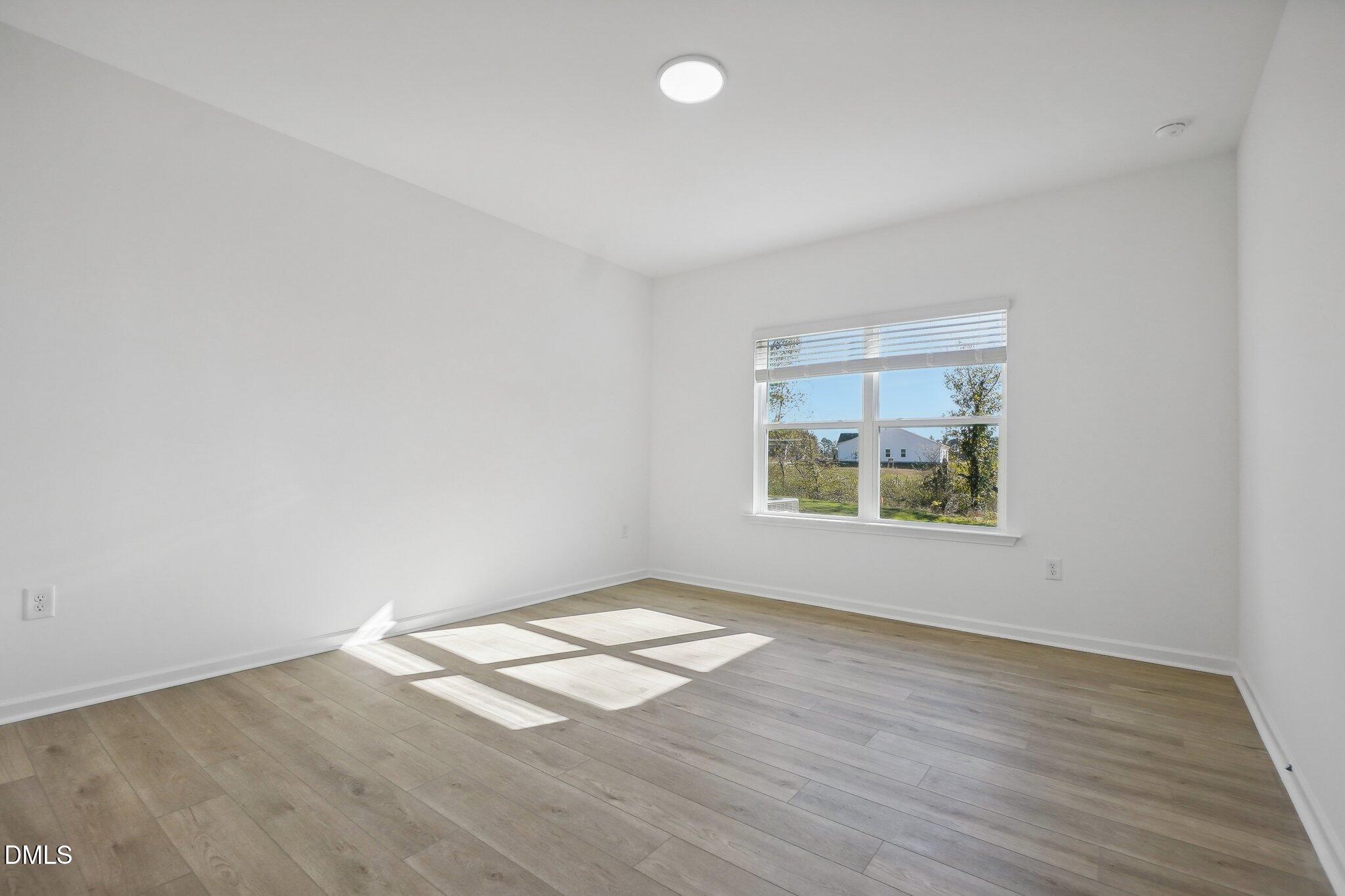 2209 Seraphic Way, Unit 402 Rolesville, NC 27571 - Photo 16 of 26 an empty room with wooden floor and windows