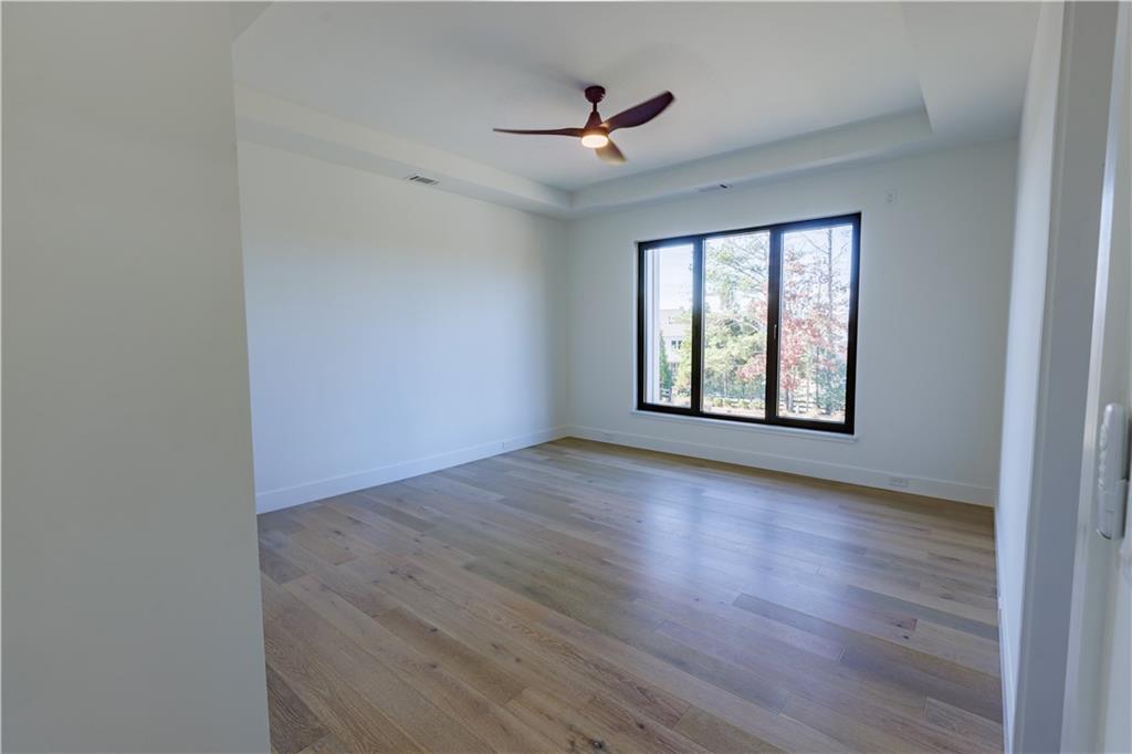 4805 Moore Road Suwanee, GA 30024 - Photo 76 of 119 an empty room with wooden floor ceiling fan and windows