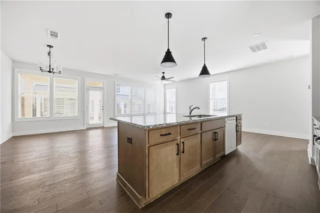 a kitchen with stainless steel appliances granite countertop a sink a window and wooden floor