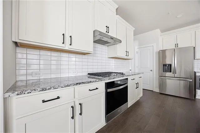 a kitchen with granite countertop white cabinets and stainless steel appliances
