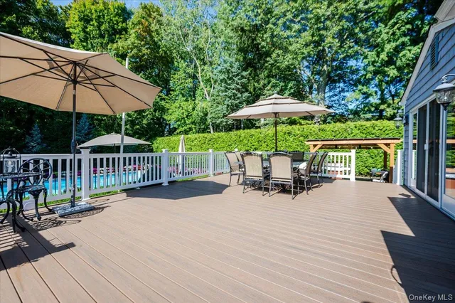 a patio with wooden floor a yard a table and chairs