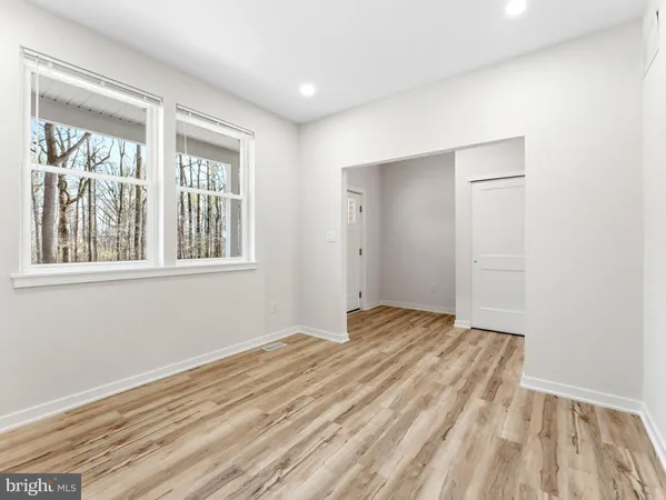 a view of an empty room with wooden floor and stairs