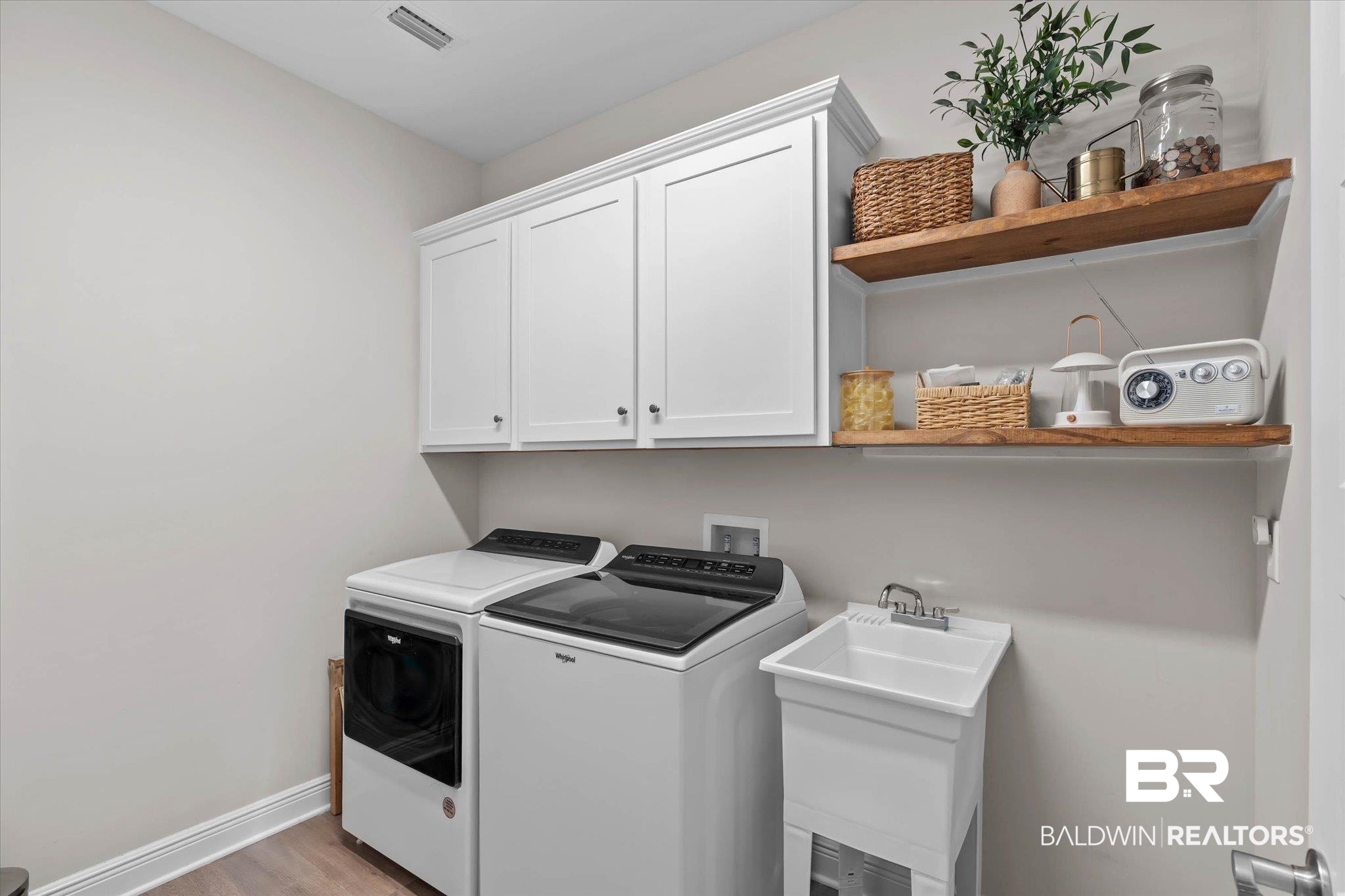 23523 Travis Stock Street Foley, AL 36535 - Photo 23 of 45 Utility room featuring white shaker cabinetry, two floating wood shelves, a utility sink, and wood-finish flooring