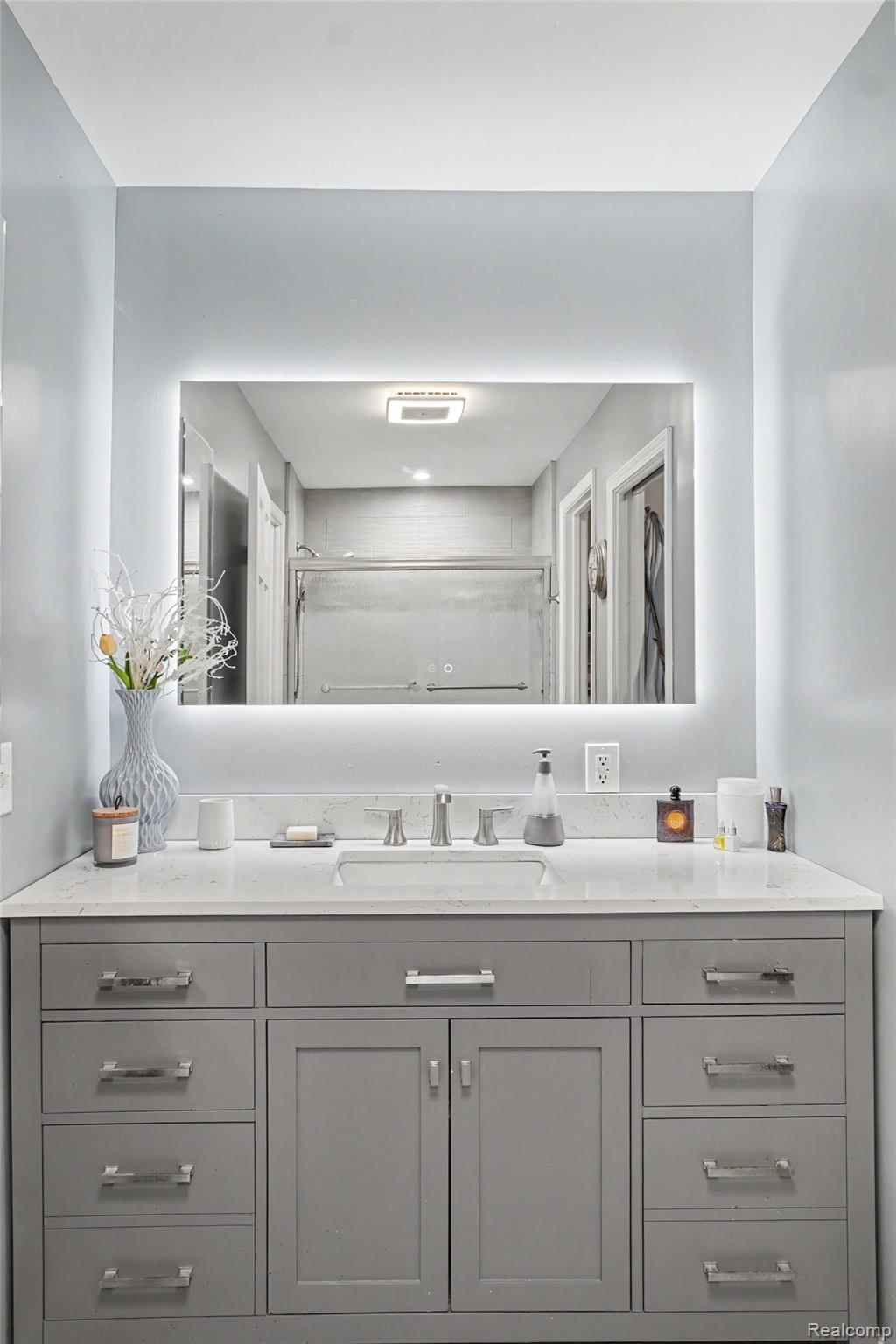 4848 Columbiaville Road Columbiaville, MI 48421 - Photo 10 of 35 Vanity featuring a light gray finish, a white countertop, and an integrated rectangular sink with a brushed nickel faucet
