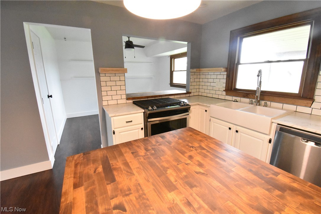 4638 Burkey Road Youngstown, OH 44515 - Photo 8 of 23 Kitchen with appliances with stainless steel finishes, white cabinets, dark hardwood floors, light countertops, and backsplash
