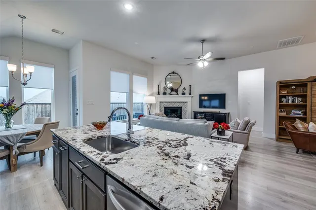 a kitchen with kitchen island granite countertop a sink cabinets and wooden floor
