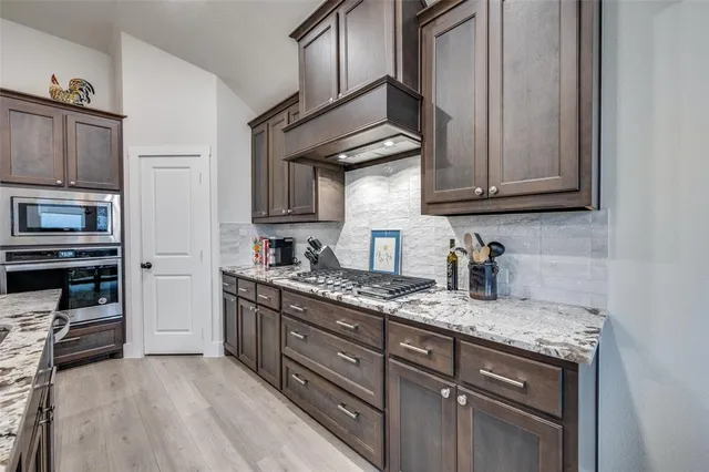 a kitchen with granite countertop stainless steel appliances a stove top oven and cabinets