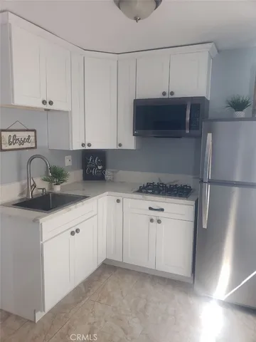 a kitchen with stainless steel appliances granite countertop white cabinets sink and a refrigerator
