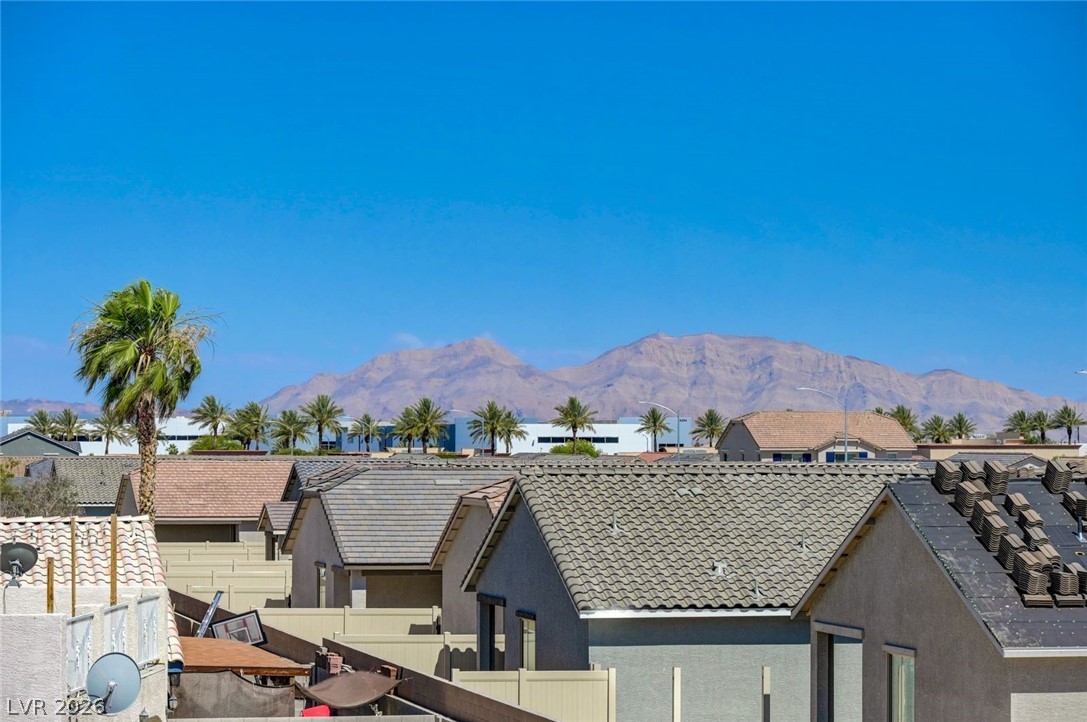 3318 North Decatur Boulevard, Unit 2072 Las Vegas, NV 89130 - Photo 2 of 50 A desert panorama showcasing community rooftops against a backdrop of distant mountains and clear skies.