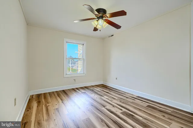 a view of room with window ceiling fan and wooden floor
