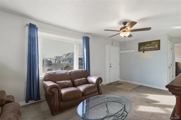 a living room with furniture a ceiling fan and a window