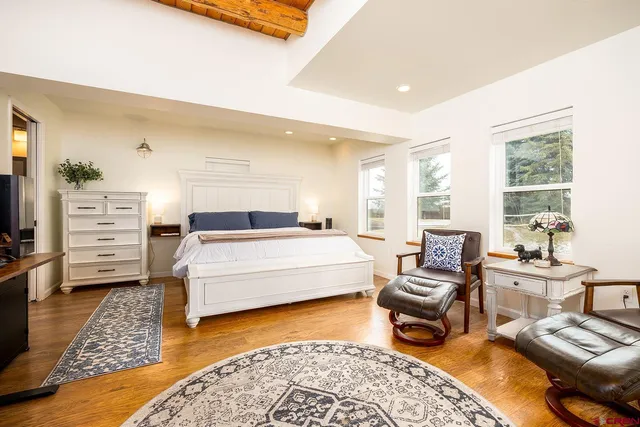 a spacious bedroom with a bed a couch and two windows