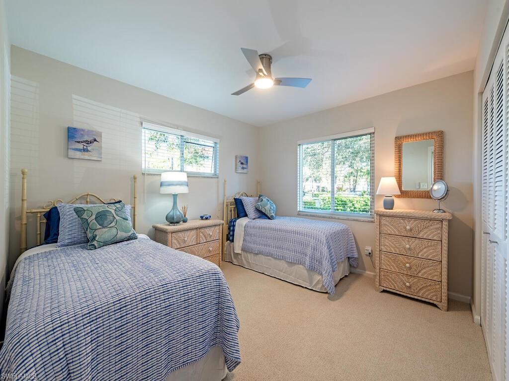 5950 Amherst Drive, Unit A106 Naples, FL 34112 - Photo 10 of 16 a bedroom with two beds and painting on the dresser