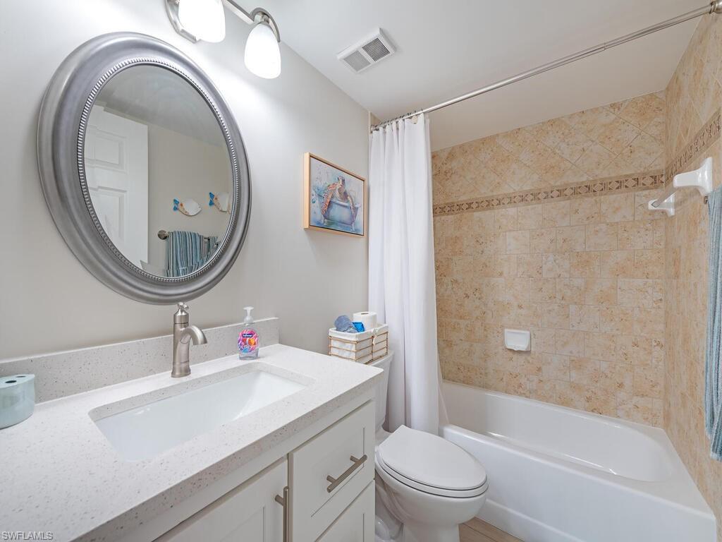 5950 Amherst Drive, Unit A106 Naples, FL 34112 - Photo 11 of 16 a bathroom with a sink a mirror a toilet and a shower