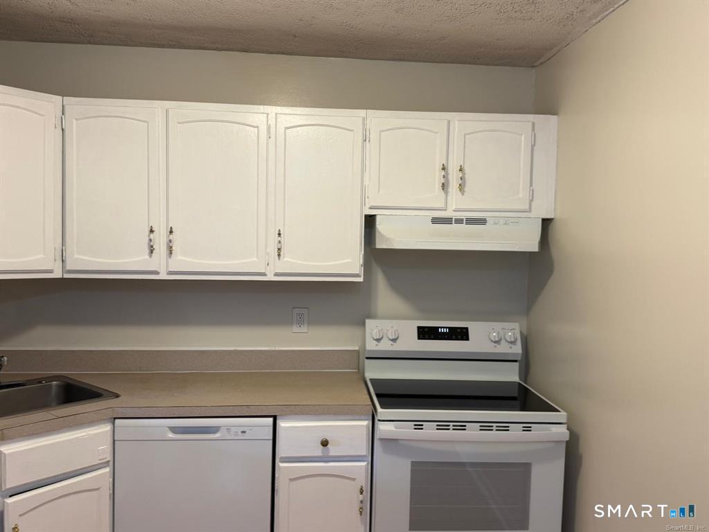 1274 East Main Street, Unit D12 Meriden, CT 06450 - Photo 6 of 14 a kitchen with white cabinets and appliances