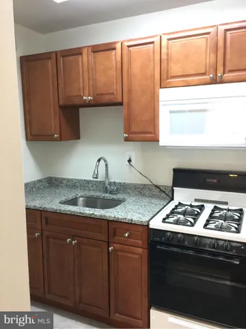 a kitchen with granite countertop wood cabinets stove and sink