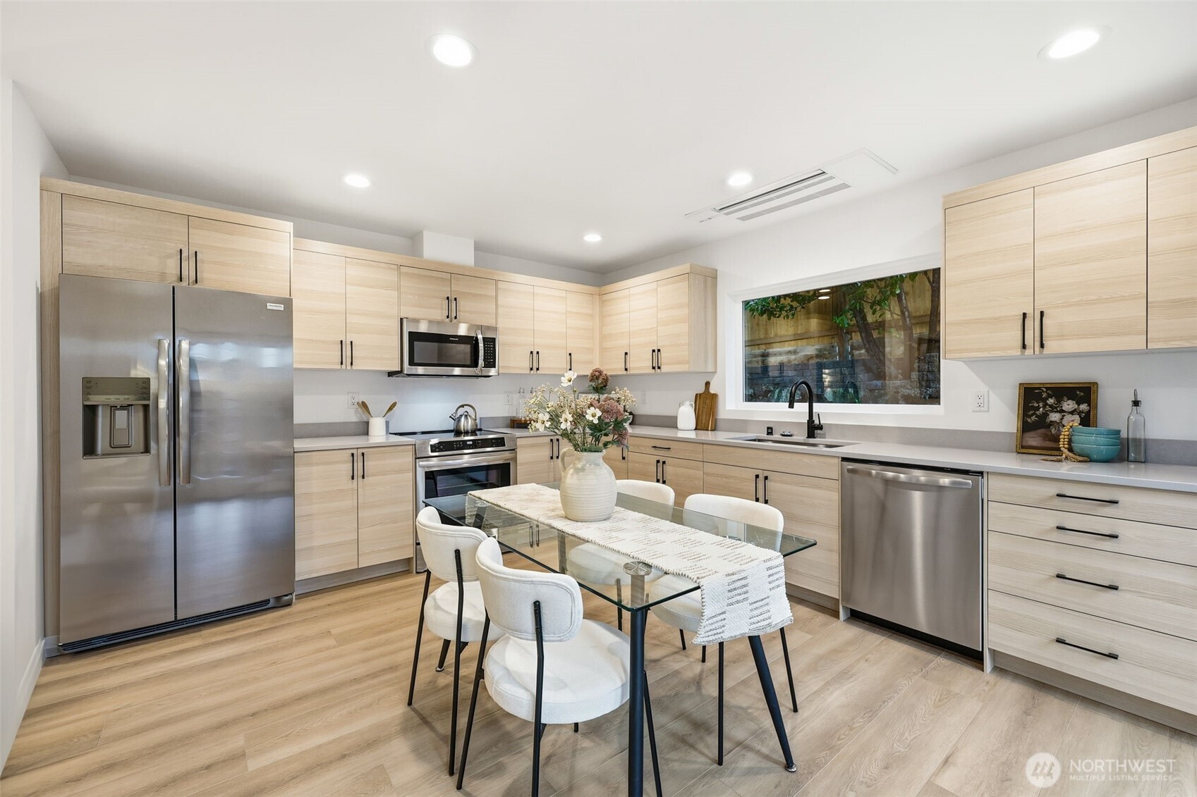 14304 1st Avenue Northwest Seattle, WA 98133 - Photo 8 of 18 a kitchen with stainless steel appliances kitchen island granite countertop a refrigerator a stove a sink a dining table and chairs with wooden floor