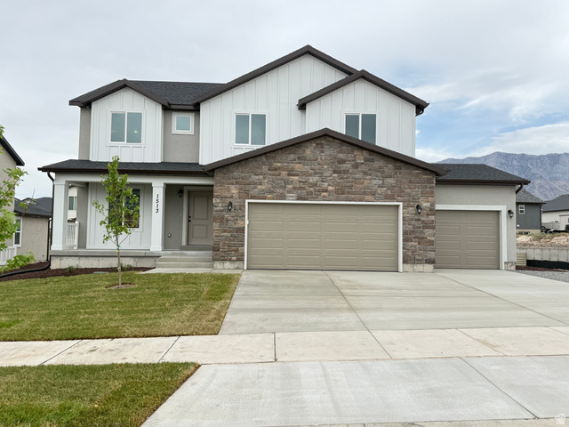 Contemporary two-story residence featuring a stone and siding exterior, an attached three-car garage, and a concrete driveway