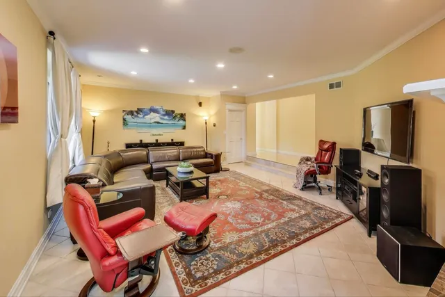 a living room with furniture a flat screen tv and a refrigerator