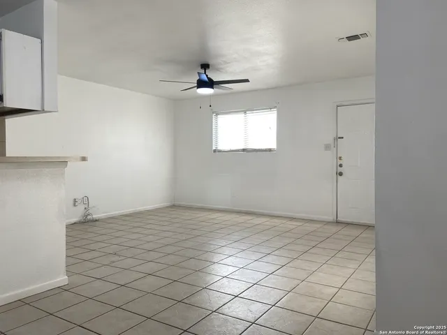 an empty room with windows and fan