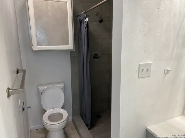 a bathroom with a granite countertop toilet and a shower