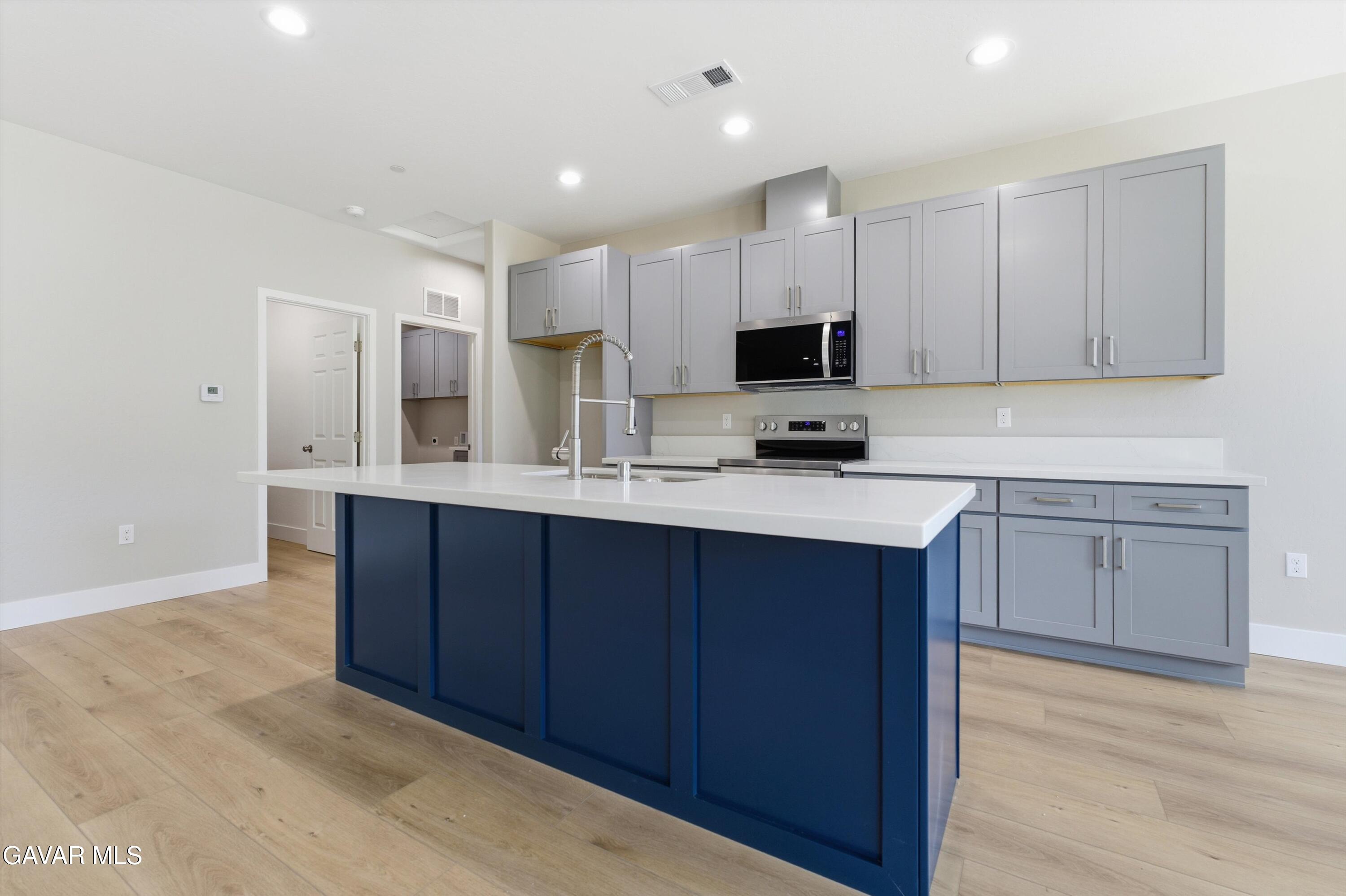 22613 Royal Place Tehachapi, CA 93561 - Photo 3 of 28 a kitchen with kitchen island granite countertop a sink cabinets and stainless steel appliances