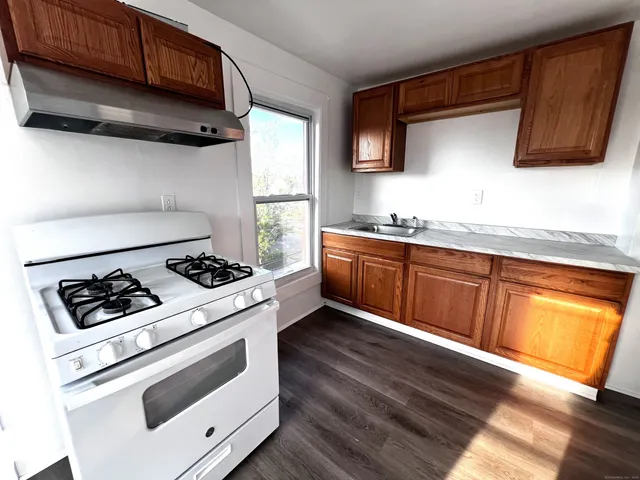 a kitchen with stainless steel appliances a stove a sink dishwasher and cabinets with wooden floor