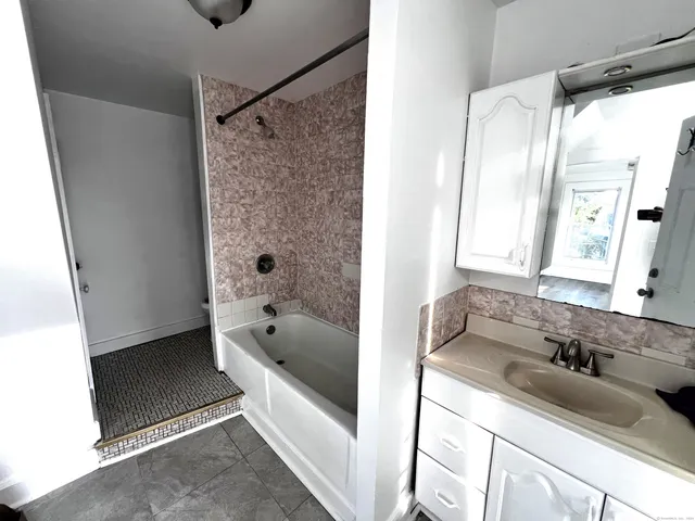 a bathroom with a tub sink and mirror