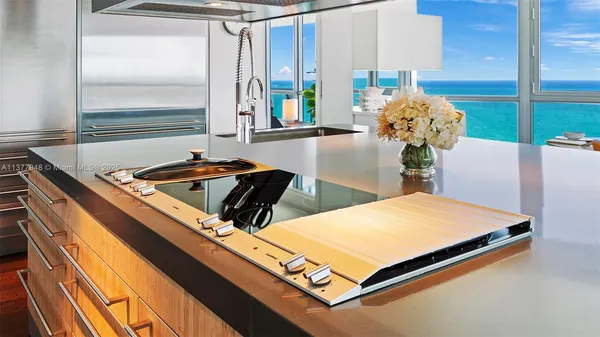 a kitchen with stainless steel appliances granite countertop a sink a stove and chairs