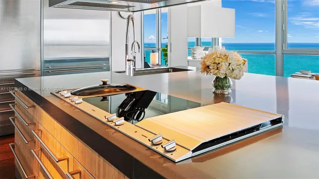 a kitchen with stainless steel appliances granite countertop a sink a stove and chairs