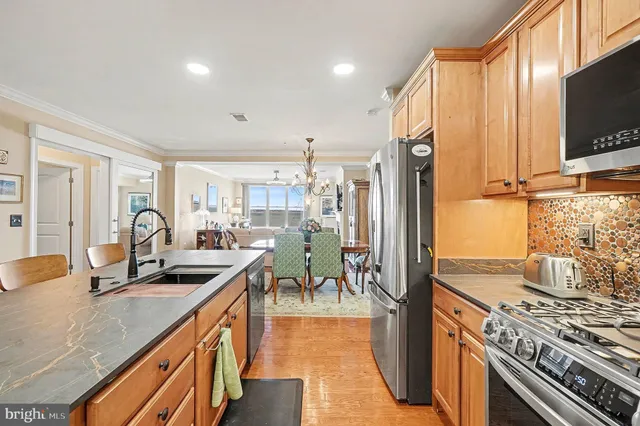 a kitchen with stainless steel appliances granite countertop a stove top oven a sink dishwasher a dining table and chairs with wooden cabinets