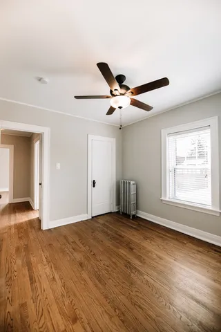 a view of an empty room with wooden floor and a window