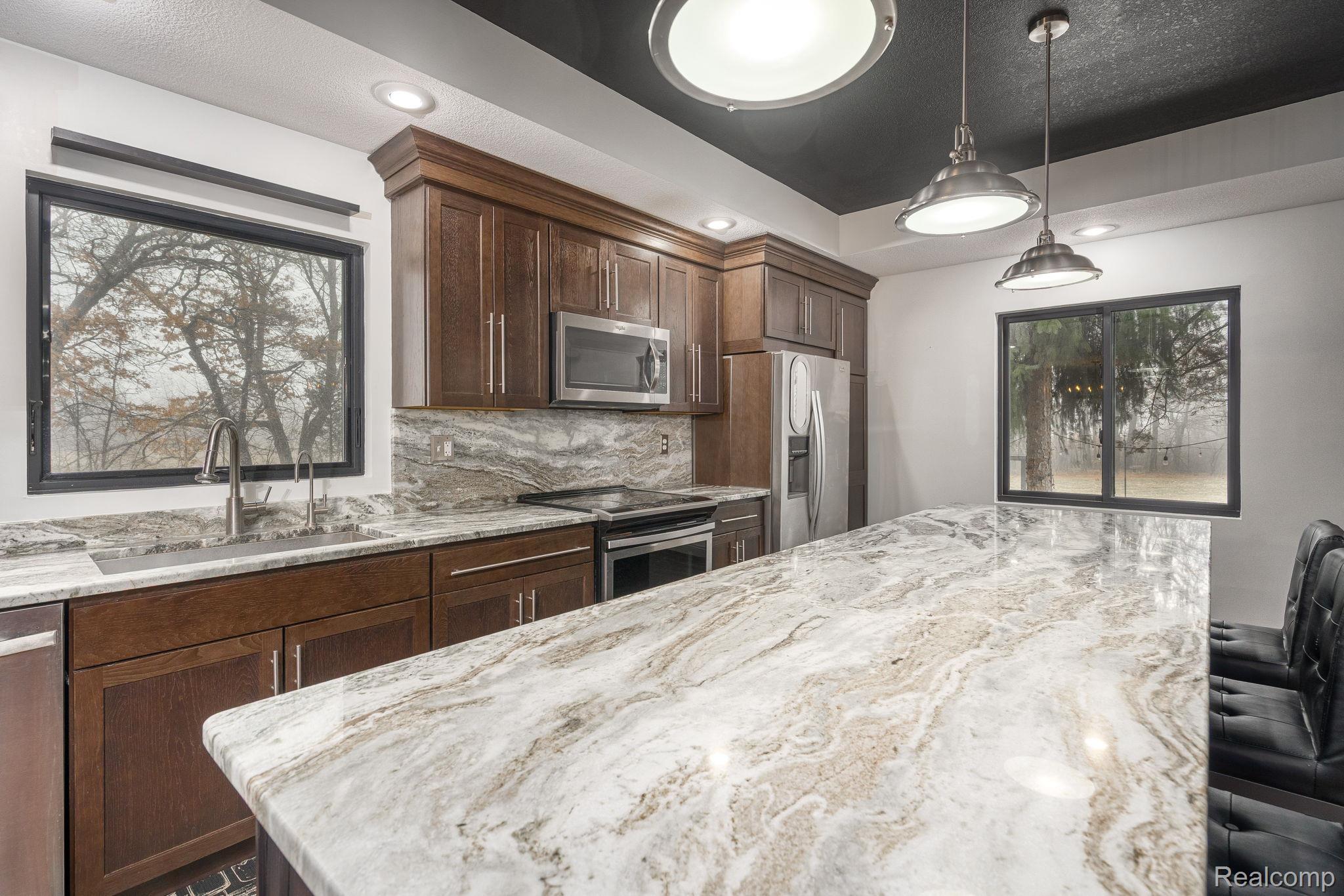 6803 Napoleon Road Jackson, MI 49201 - Photo 20 of 59 Kitchen with a breakfast bar, stainless steel appliances, plenty of natural light, light stone countertops, and a textured ceiling